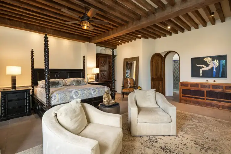 Casa Cañadita, bedroom with a four-poster bed, cream chairs and a wood beam ceiling, San Miguel de Allende