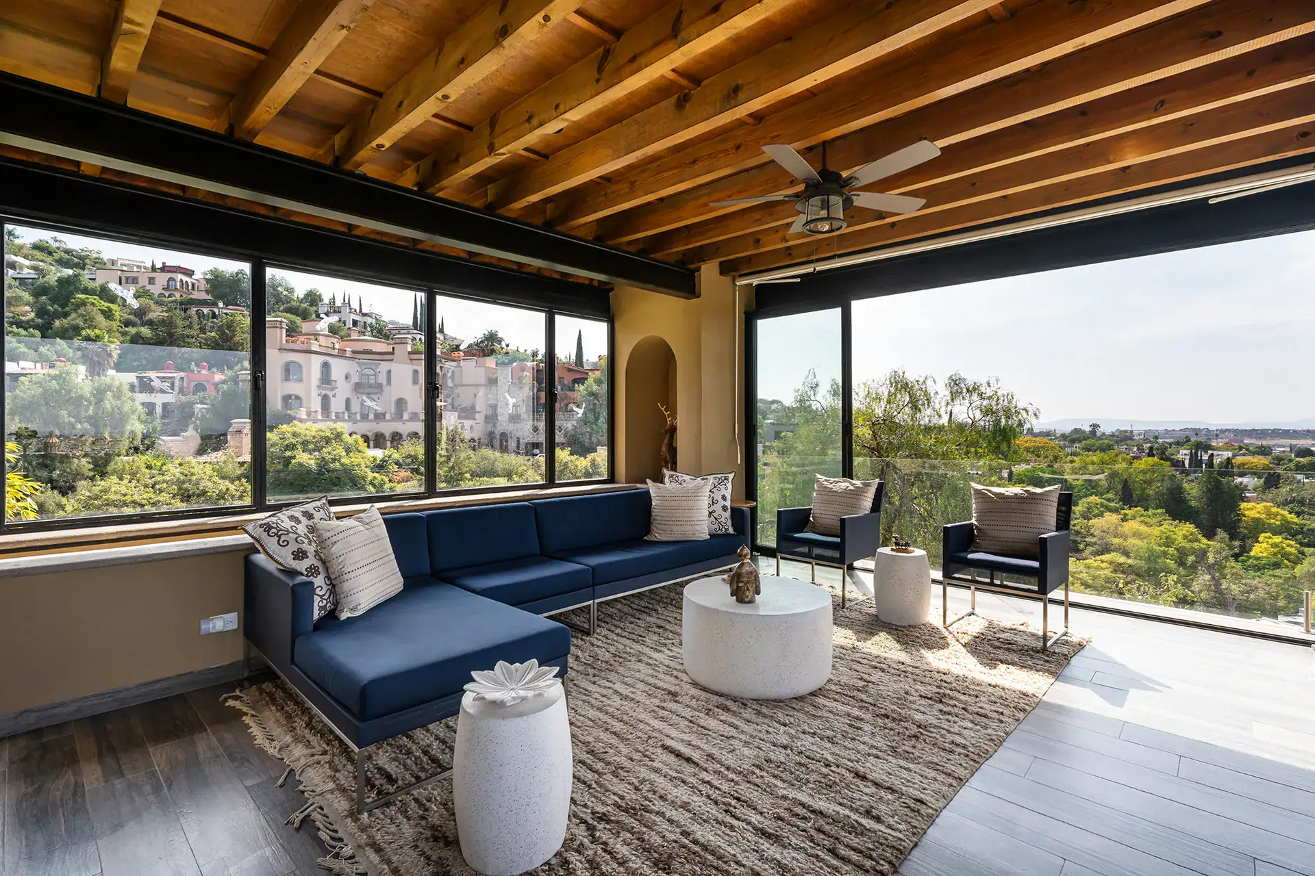 Casa Cañadita, glass-walled living room with navy sofas and a view of the valley, San Miguel de Allende