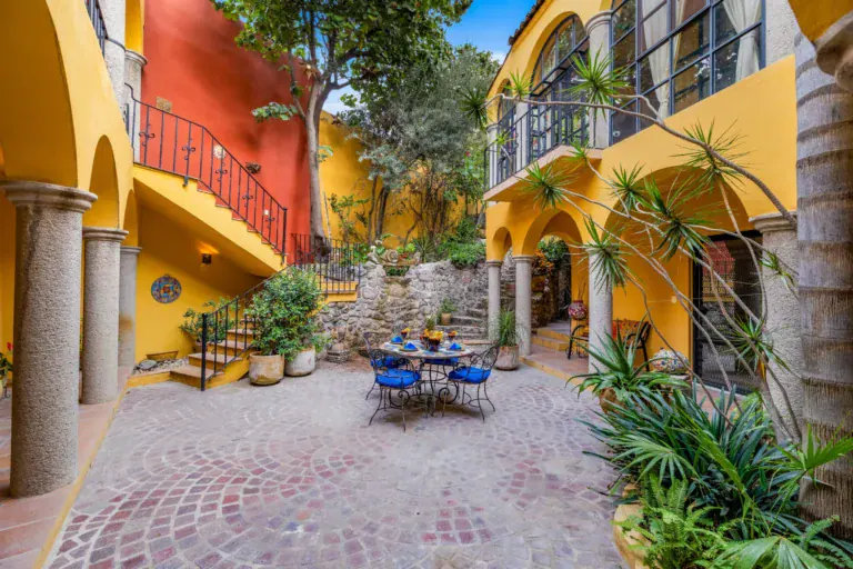 Casa Caracol Rojo, courtyard with a red staircase and a round mosaic table, San Miguel de Allende