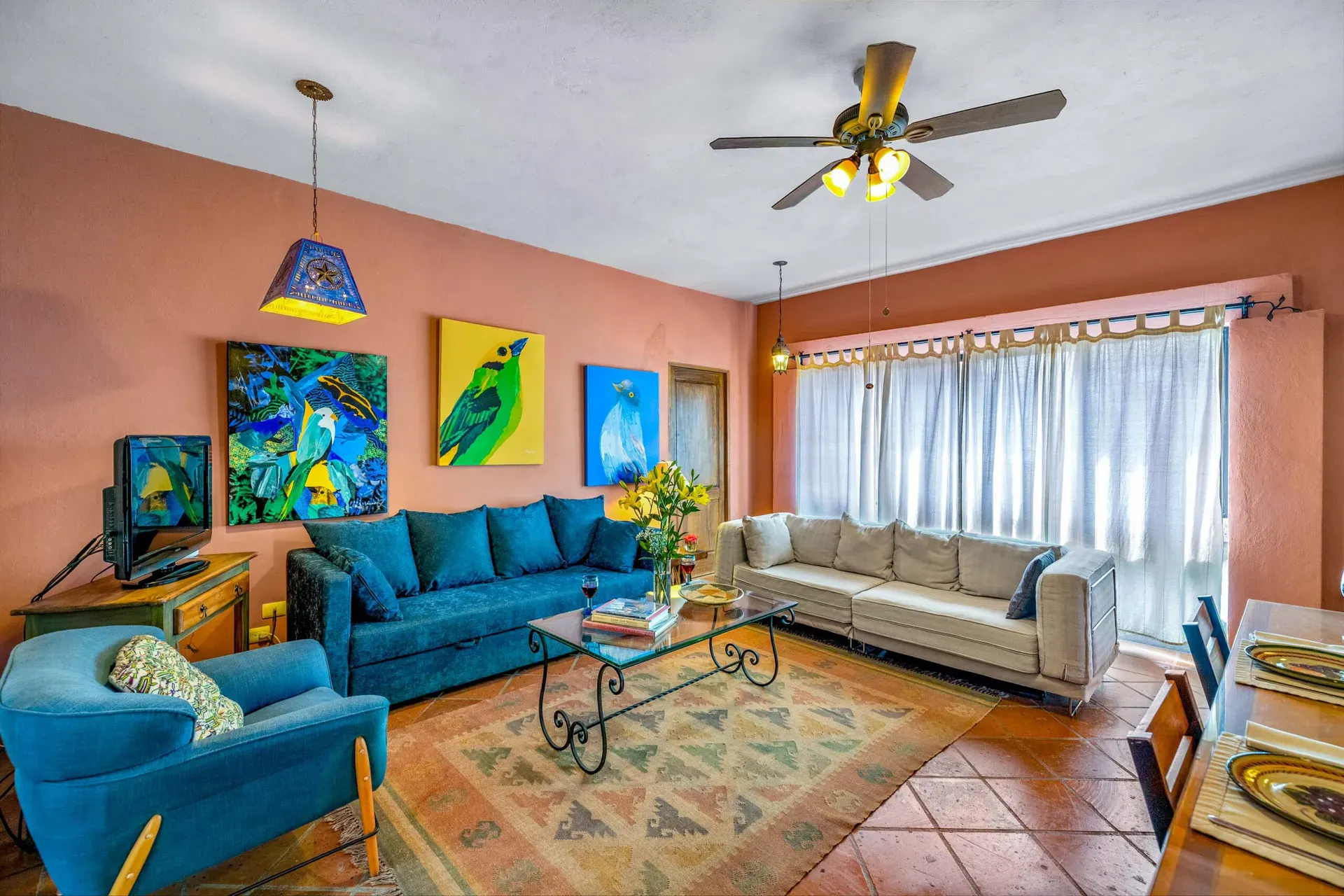 Casa Caracol Rojo, living room with a blue sofa and colorful bird paintings, San Miguel de Allende