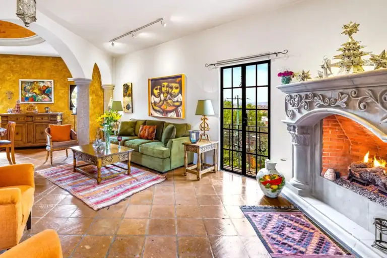 Casa Caracol Rojo, great room with a stone fireplace and arched black steel doors, San Miguel de Allende