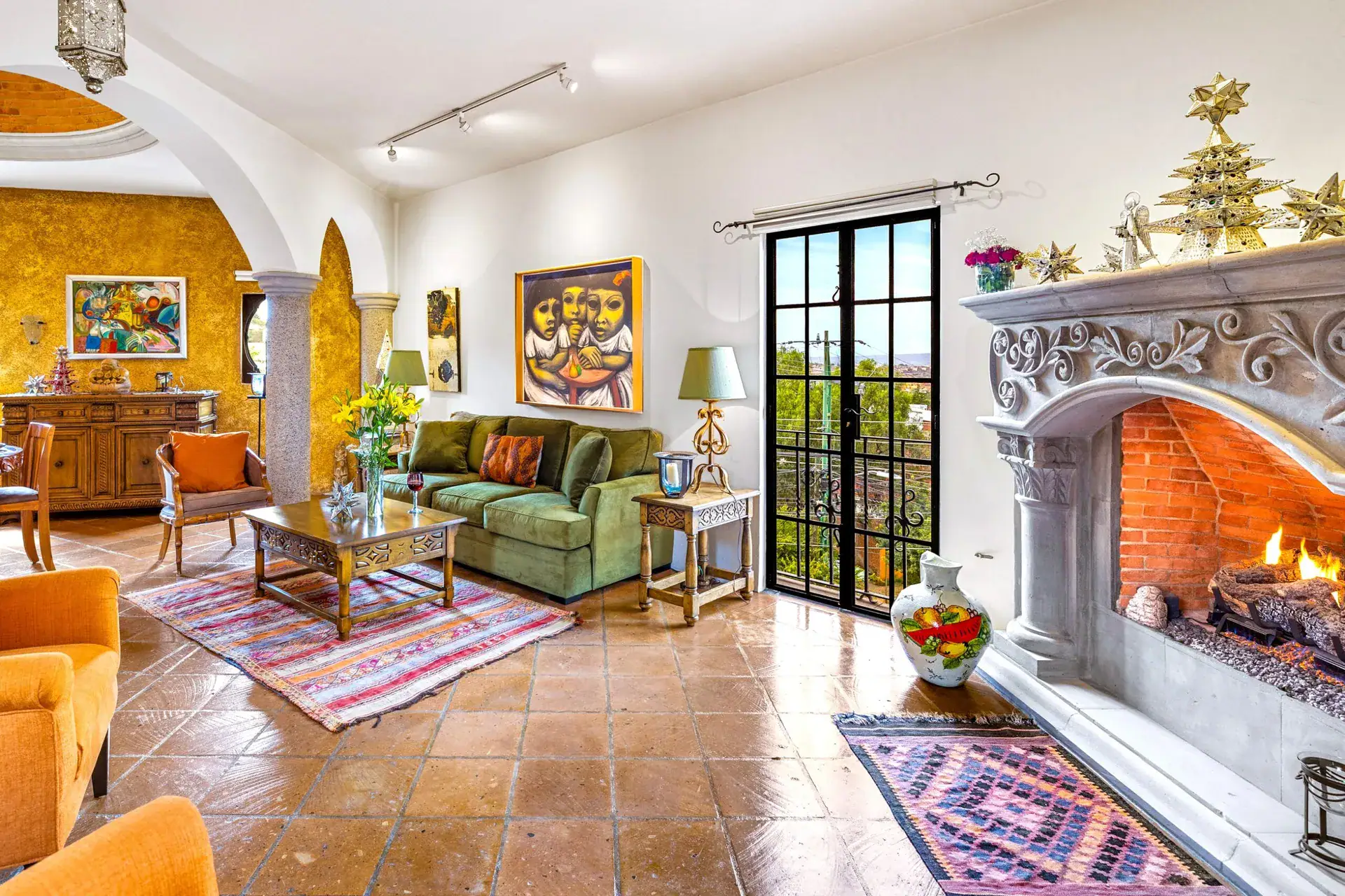 Casa Caracol Rojo, great room with a stone fireplace and arched black steel doors, San Miguel de Allende