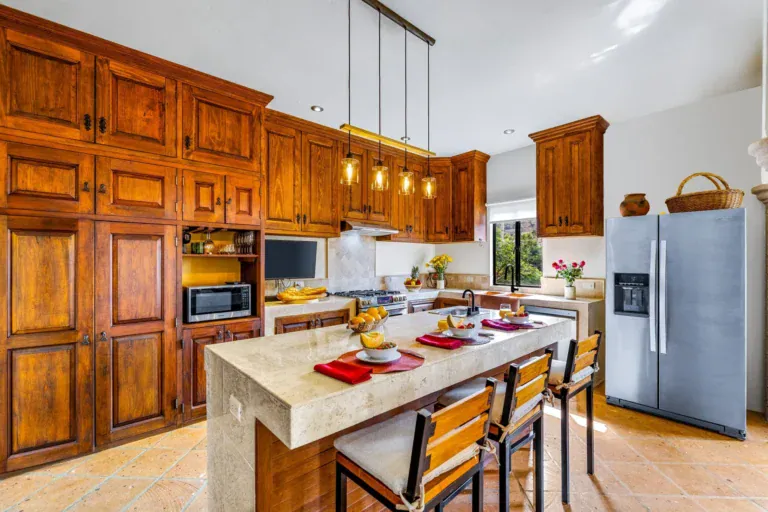Casa Caracol Rojo, kitchen with wood cabinets, a large island and a steel refrigerator, San Miguel de Allende