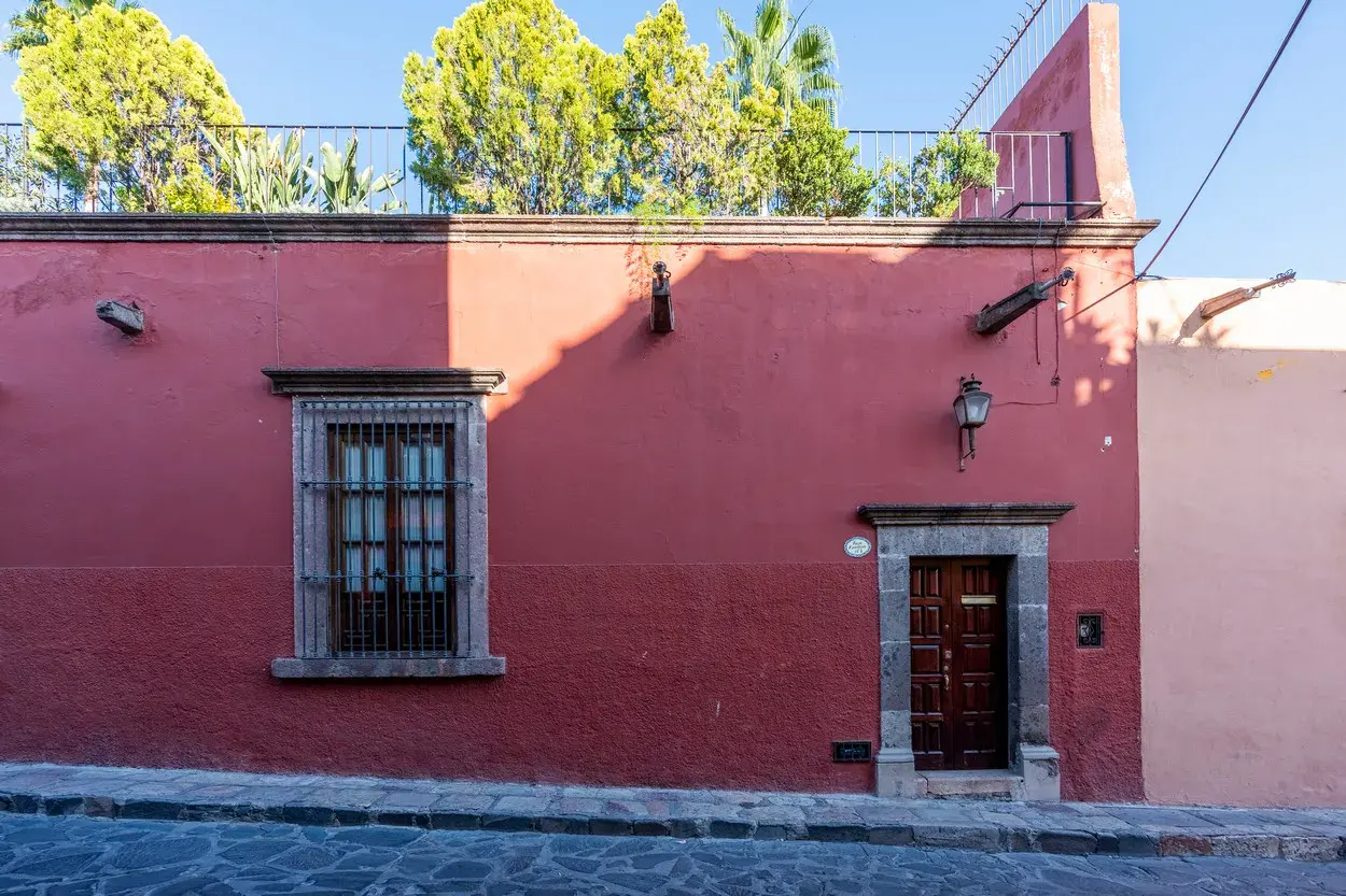 Casa Carolina, red stucco street facade with a carved stone door frame, San Miguel de Allende