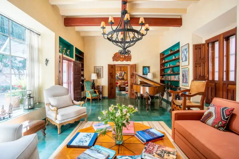 Casa Carolina, living room with a chandelier, teal floor and cream armchairs, San Miguel de Allende