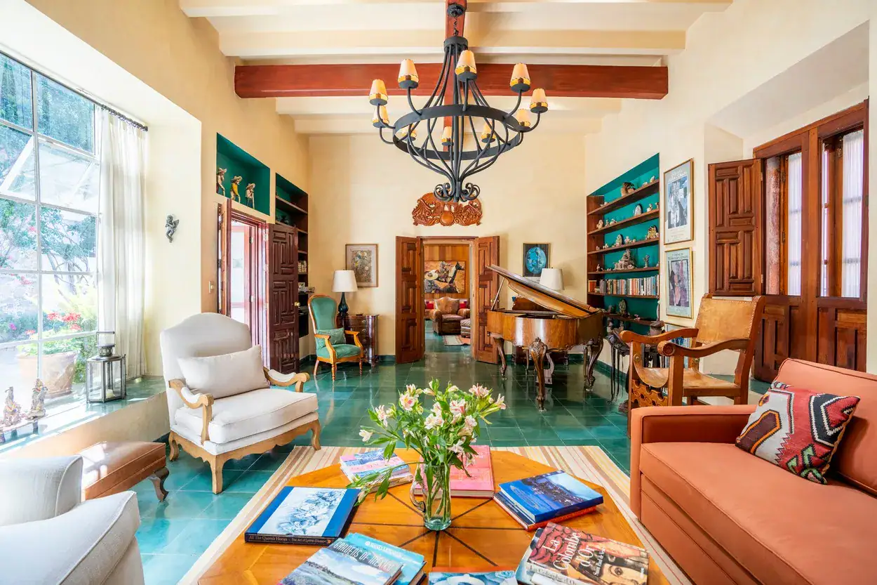 Casa Carolina, living room with a chandelier, teal floor and cream armchairs, San Miguel de Allende