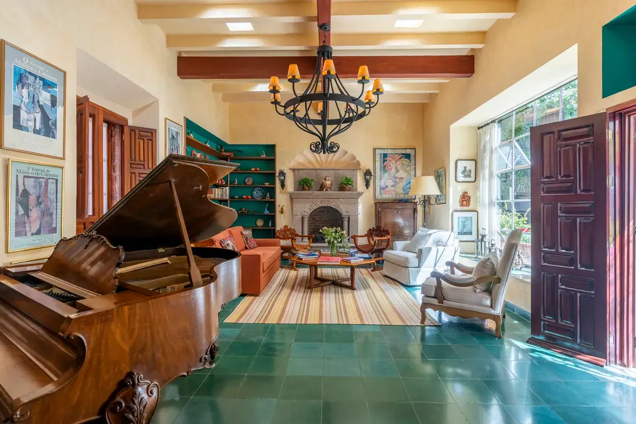 Casa Carolina, music room with a grand piano, a fireplace and teal built-in shelves, San Miguel de Allende