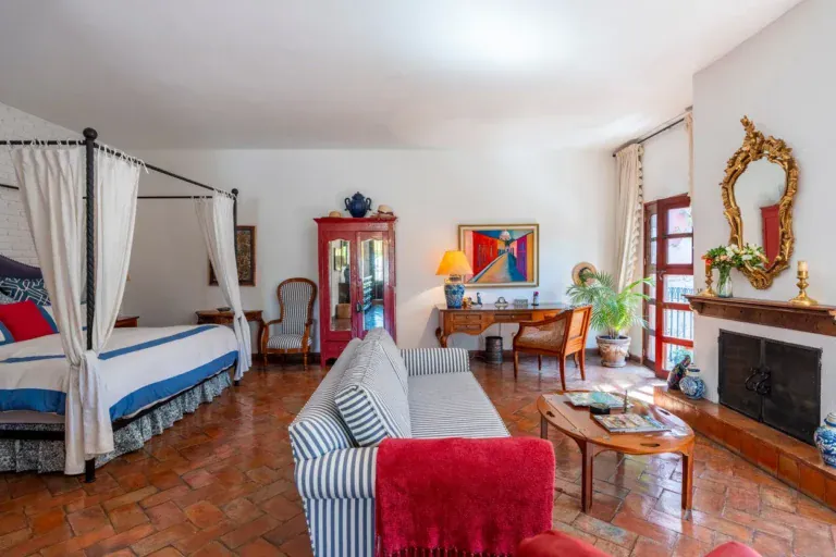 Casa Carolina, bedroom with a canopy bed, a fireplace and striped sofas, San Miguel de Allende