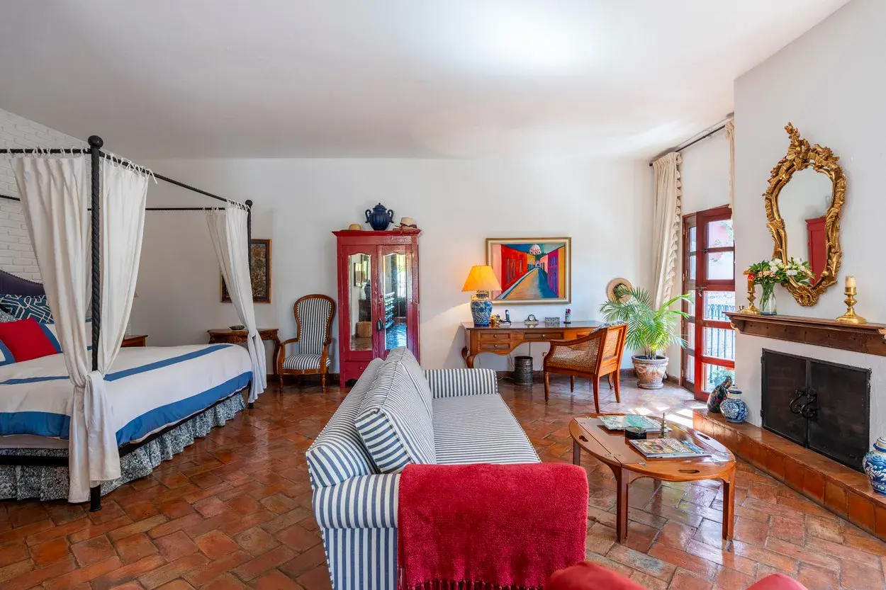 Casa Carolina, bedroom with a canopy bed, a fireplace and striped sofas, San Miguel de Allende