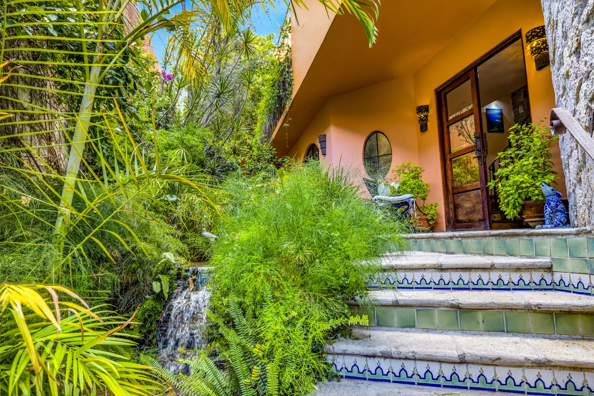 Casa Cascada, entry stairway with tiled steps, a small waterfall and a glass door among tropical plants, San Miguel de Allende