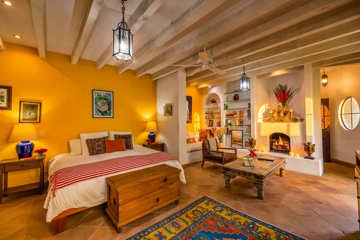 Casa Cascada, guest suite with a yellow wall, a bed, a fireplace and a lantern pendant, San Miguel de Allende