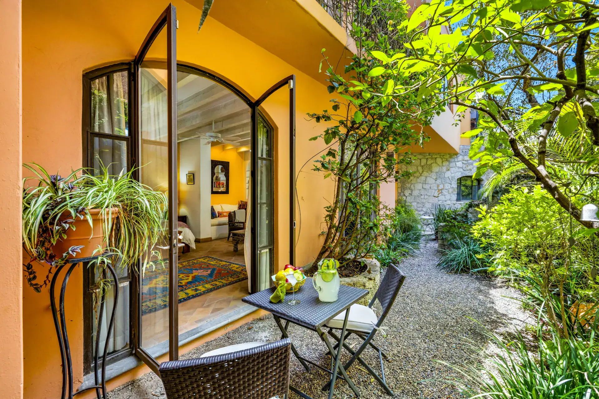 Casa Cascada, glass doors from the guest suite opening to a gravel garden patio with a bistro table, San Miguel de Allende