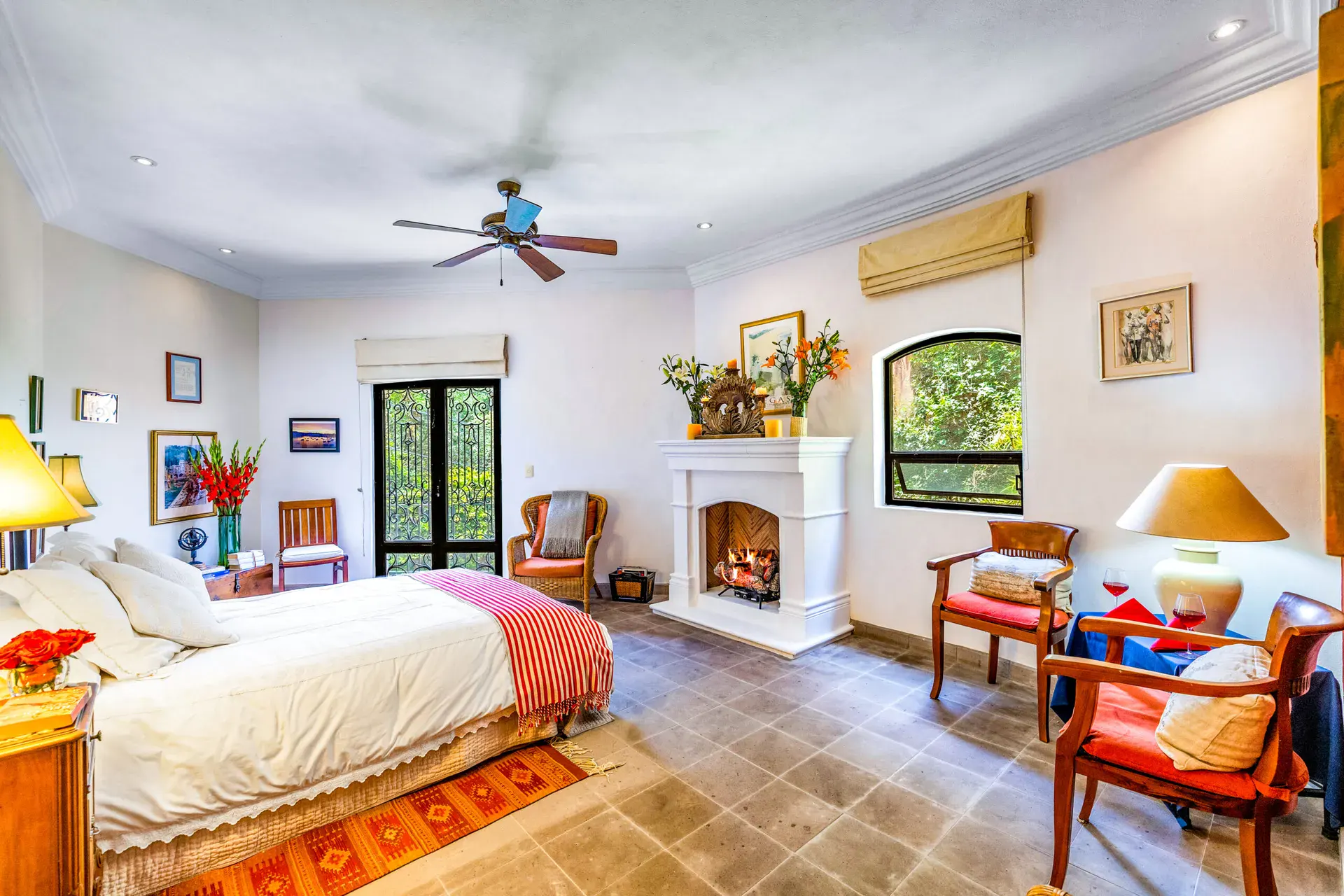 Casa Cascada, primary bedroom with a stone fireplace, a seating area, a ceiling fan and a garden view, San Miguel de Allende
