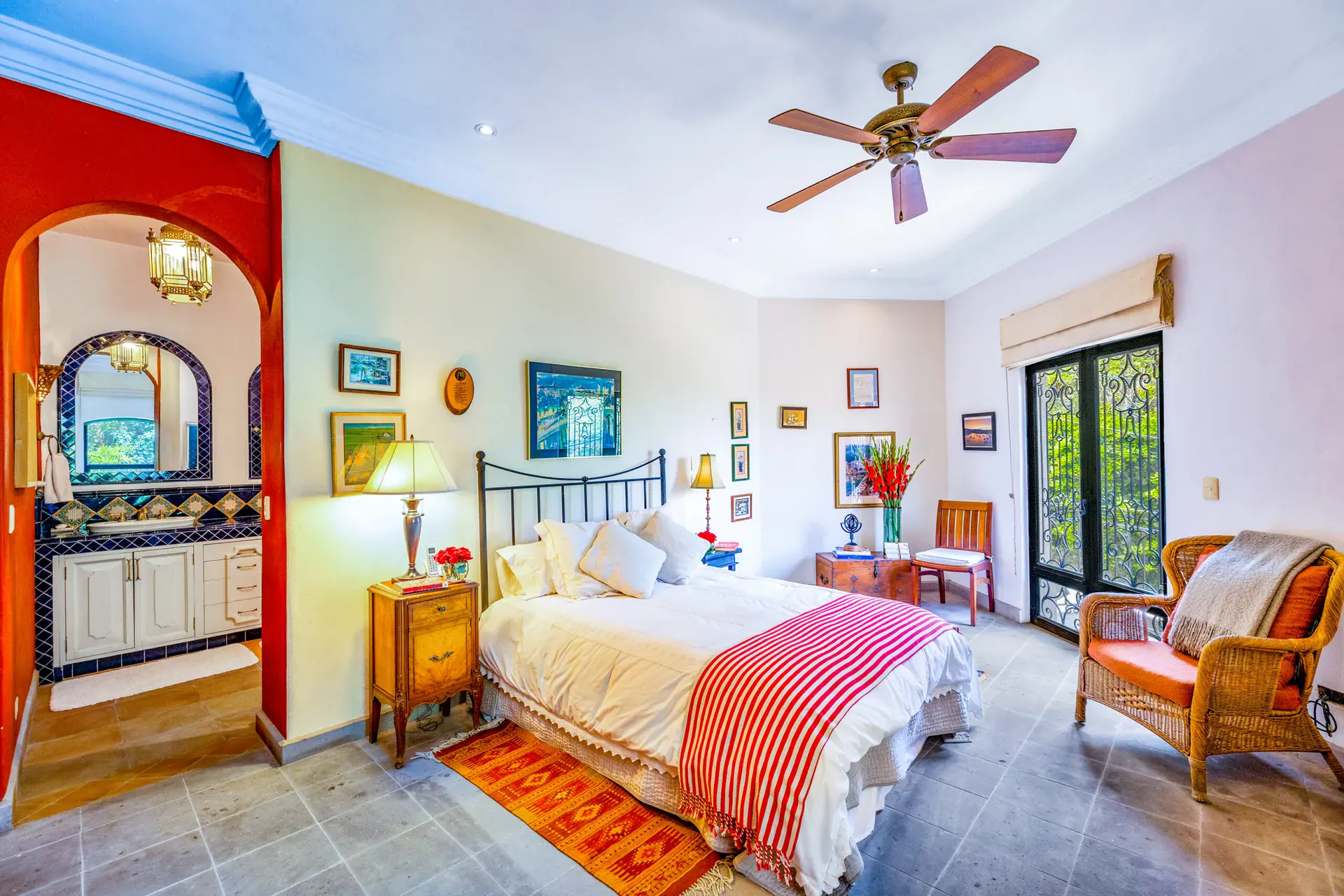 Casa Cascada, bedroom with a wrought-iron bed, a blue tile vanity niche and glass doors to the garden, San Miguel de Allende