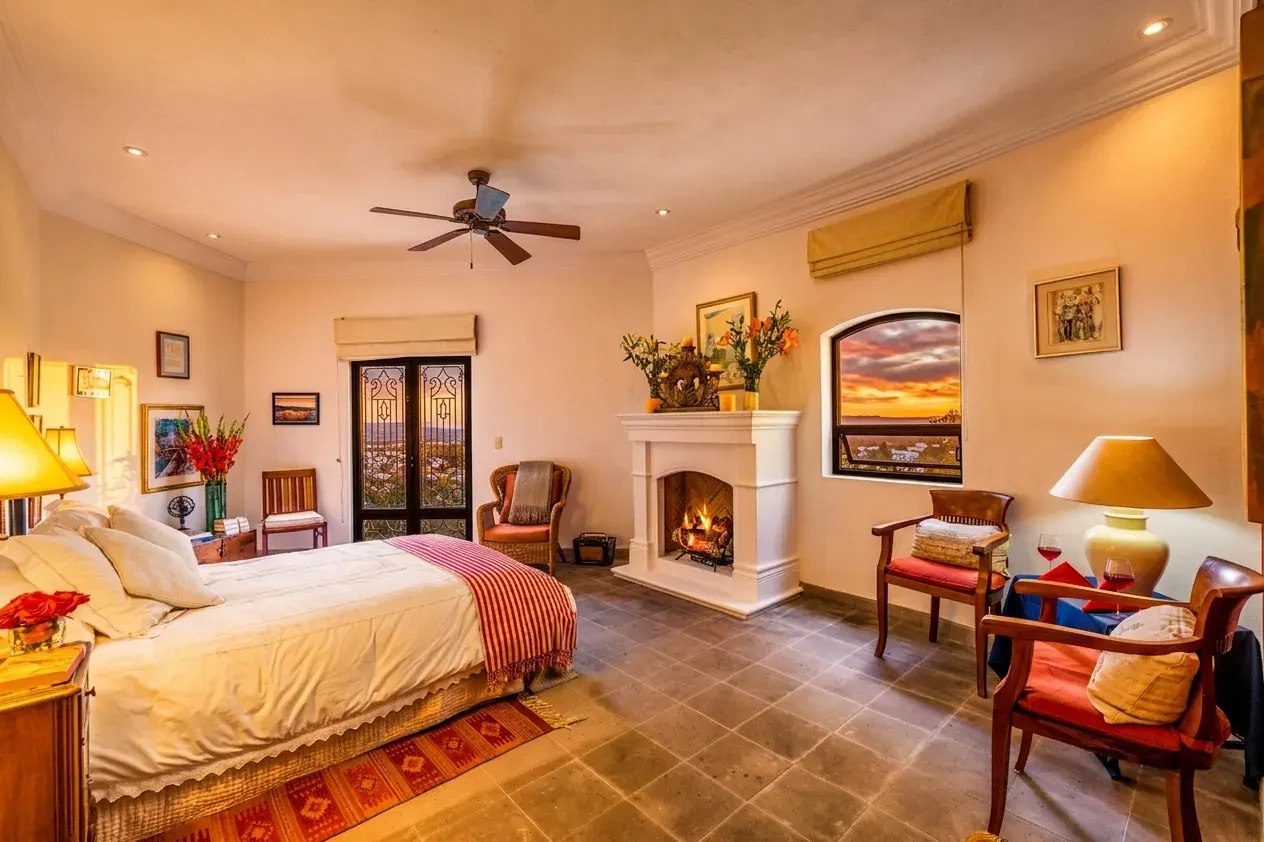 Casa Cascada, bedroom with a fireplace, a view of a sunset through a window and a ceiling fan, San Miguel de Allende