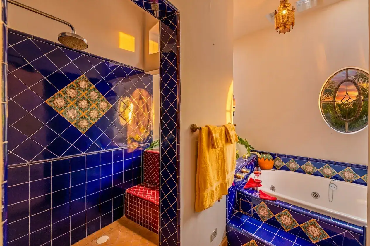 Casa Cascada, blue tile shower and whirlpool tub with a stained glass window and a yellow towel, San Miguel de Allende