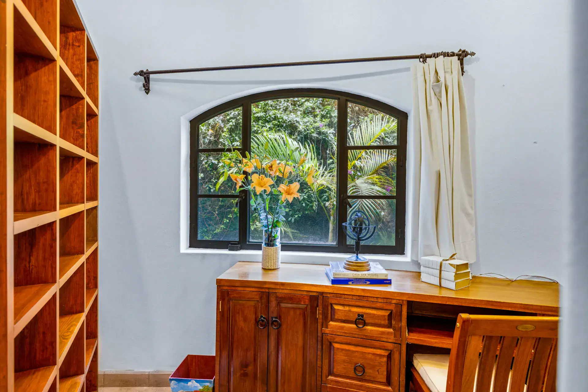 Casa Cascada, built-in wood shelves and a wood desk below an arched window with garden views, San Miguel de Allende
