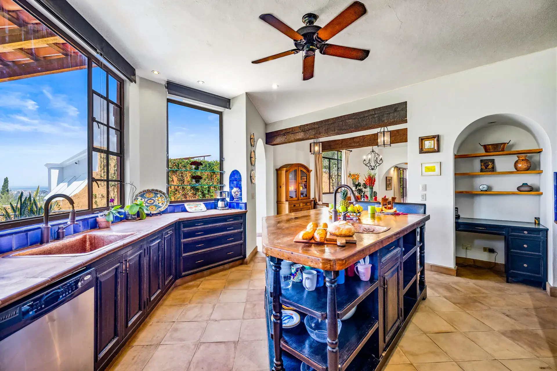 Casa Cascada, kitchen with a copper sink, a blue island with open shelves, and a large window to the view, San Miguel de Allende