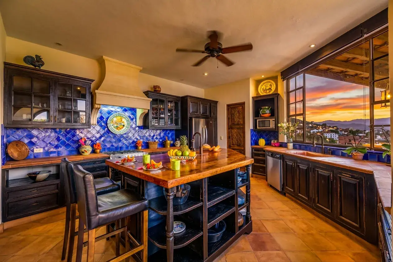 Casa Cascada, kitchen at sunset with a blue tile backsplash, a wood island and a ceiling fan, San Miguel de Allende