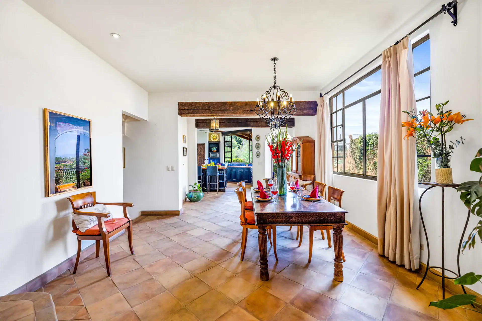 Casa Cascada, dining room and kitchen beyond, with a wood table and large windows, San Miguel de Allende