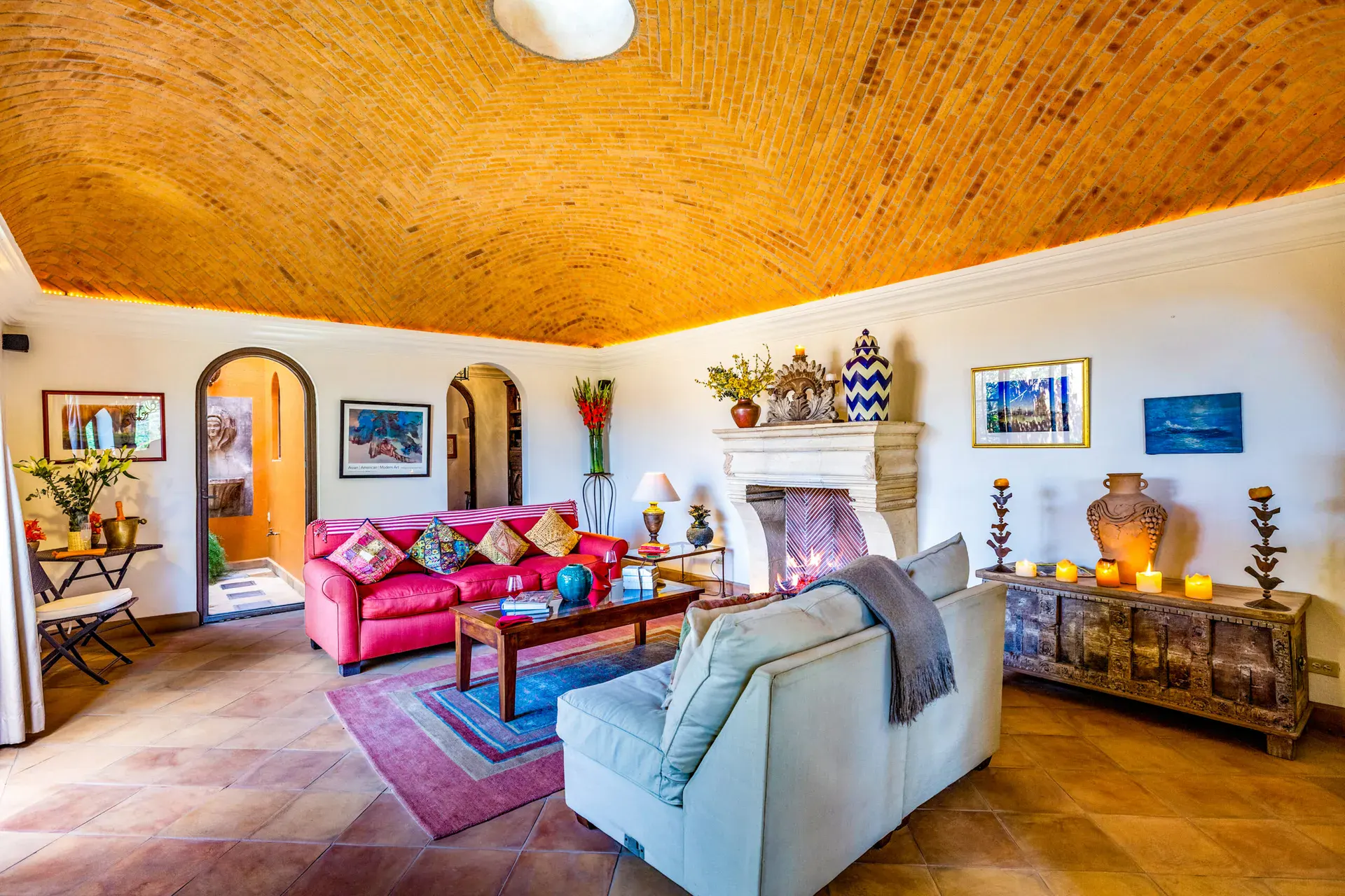 Casa Cascada, living room with a brick vaulted ceiling, a stone fireplace, a pink leather sofa and a white sofa, San Miguel de Allende