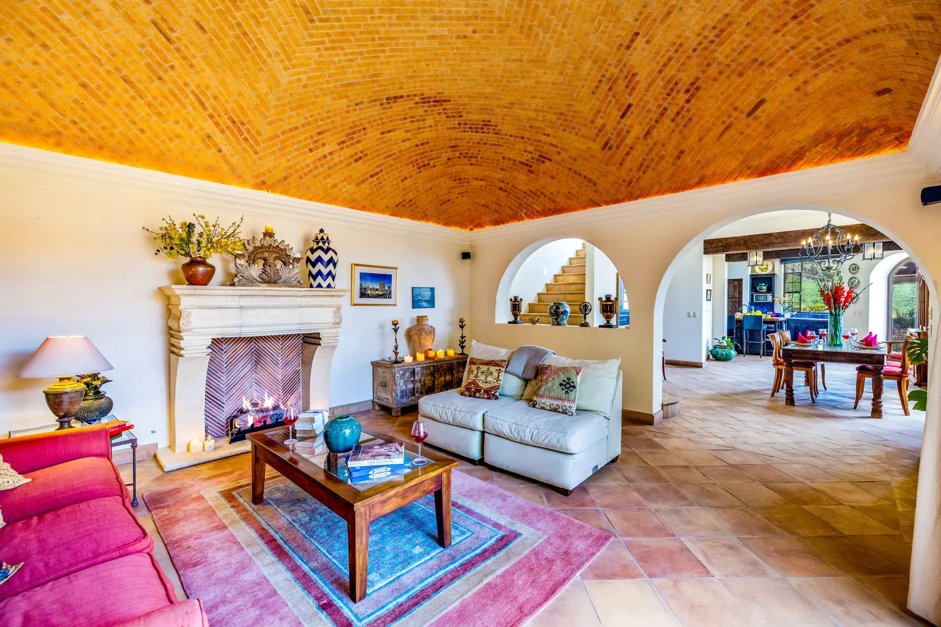 Casa Cascada, living room with arched openings, a lit stone fireplace and pink leather sofas, San Miguel de Allende