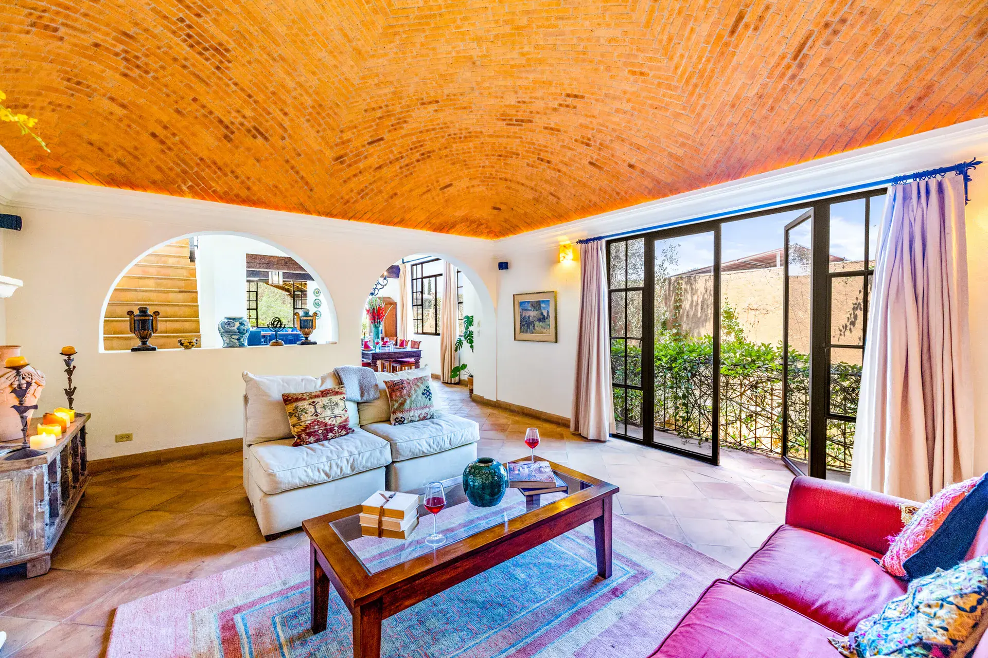 Casa Cascada, living room with a brick vaulted ceiling, a white sofa and sliding glass doors to a terrace, San Miguel de Allende