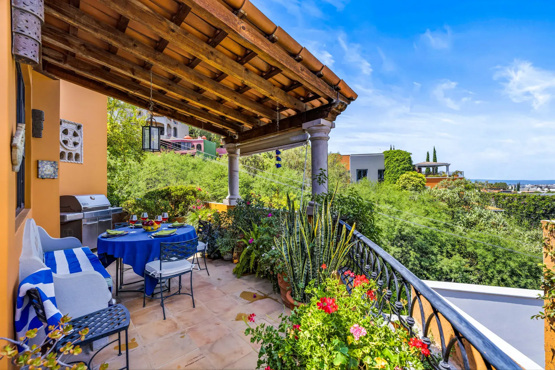 Casa Cascada, covered terrace with a grill, a table with blue cloth and a striped bench overlooking the hills, San Miguel de Allende
