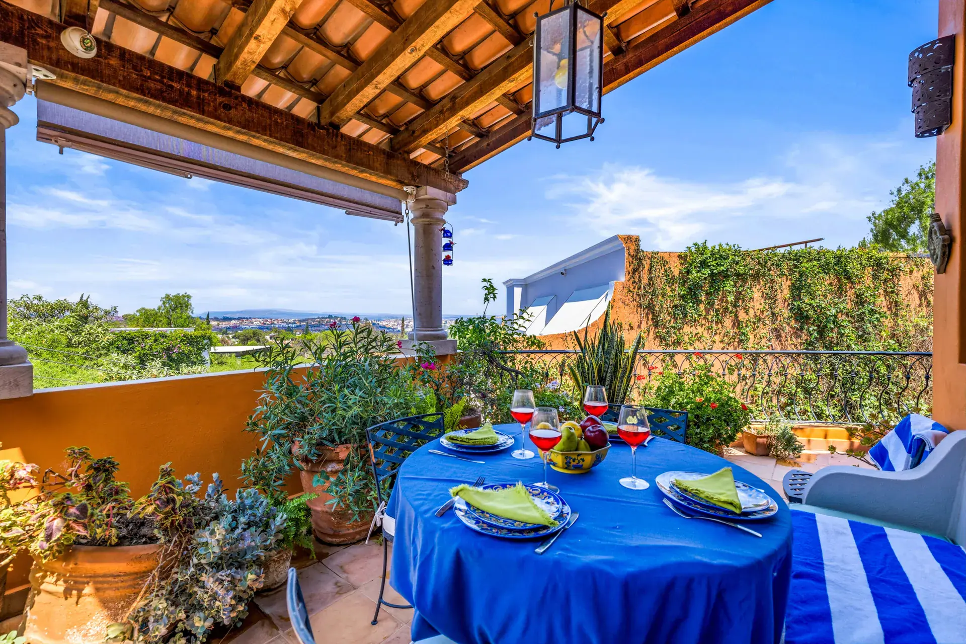 Casa Cascada, covered terrace at golden hour with a set table, cushioned bench and a view across the valley, San Miguel de Allende