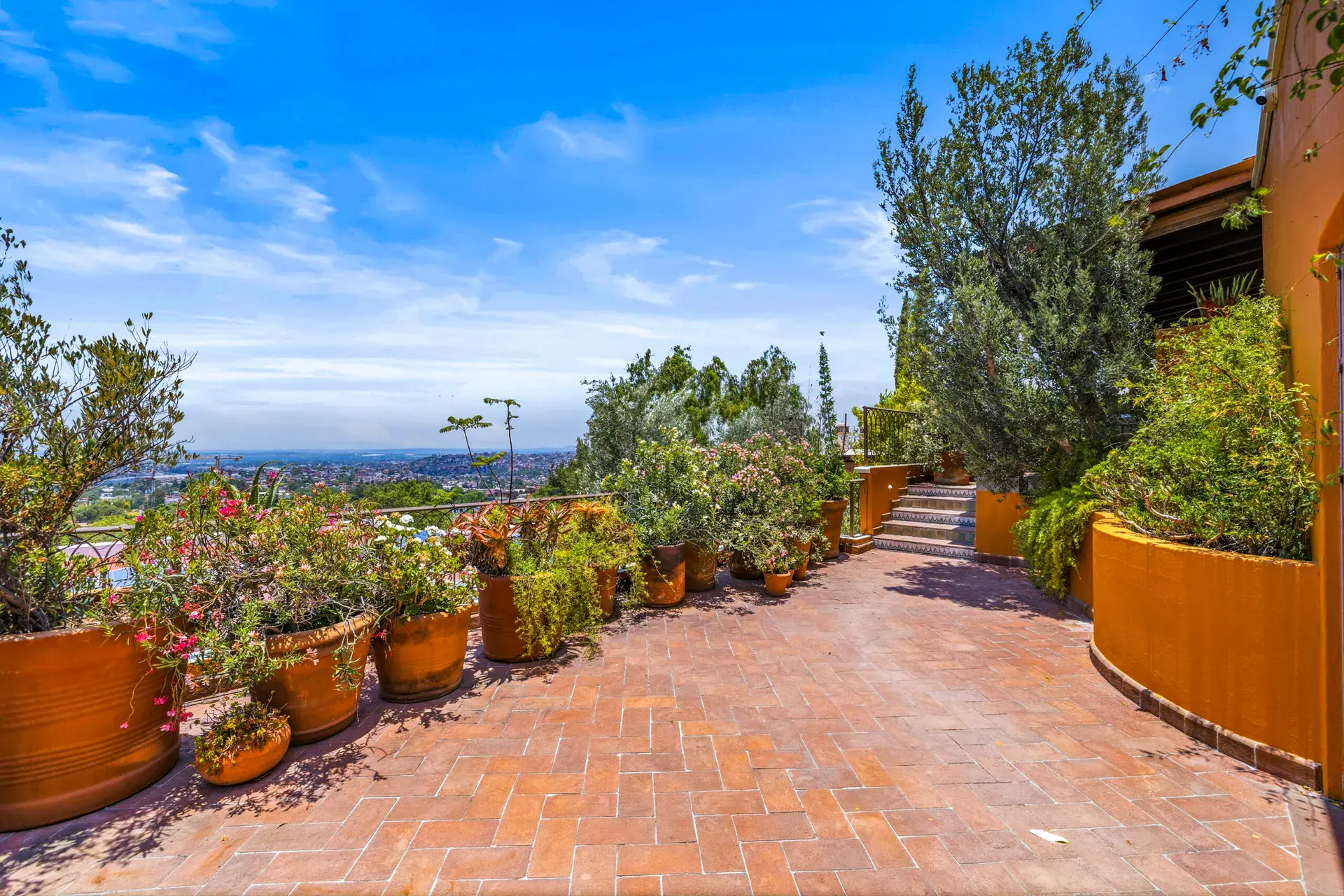 Casa Cascada, brick-paved terrace with potted plants and a view of the valley, San Miguel de Allende