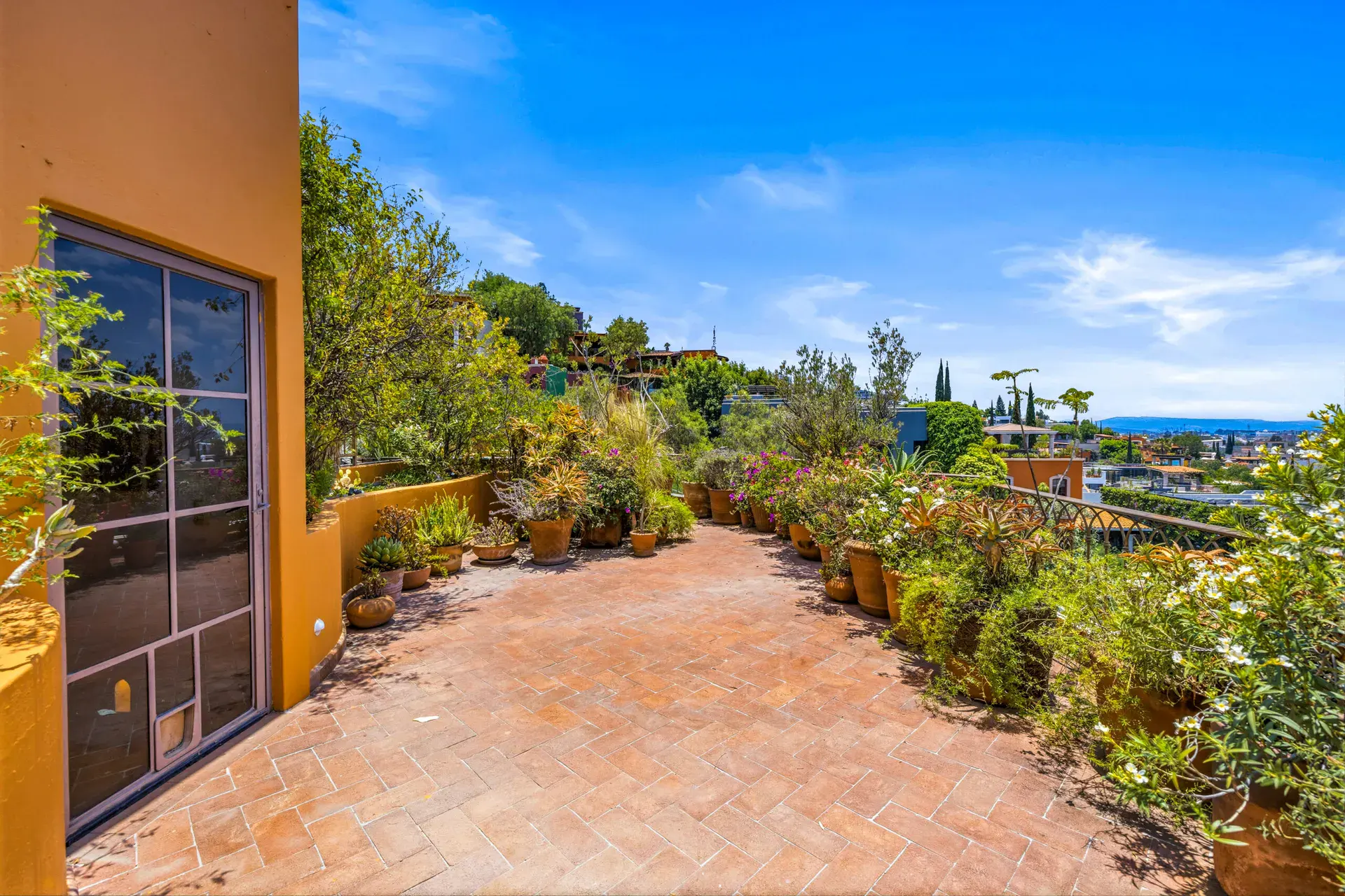 Casa Cascada, long terrace with a brick herringbone floor, bougainvillea and potted plants, San Miguel de Allende
