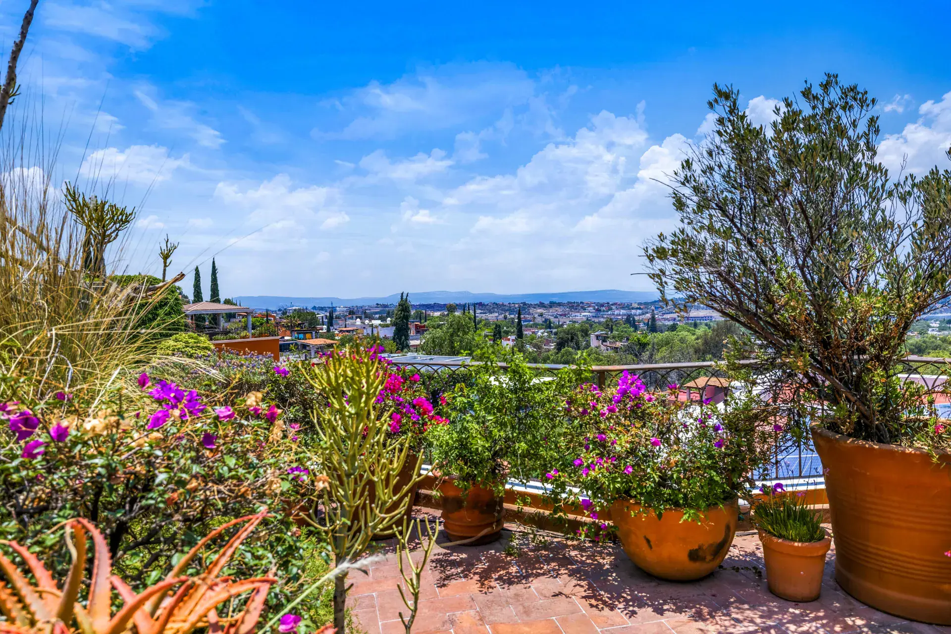 Casa Cascada, terrace with flowering bougainvillea and two bar stools at a small table over the valley, San Miguel de Allende