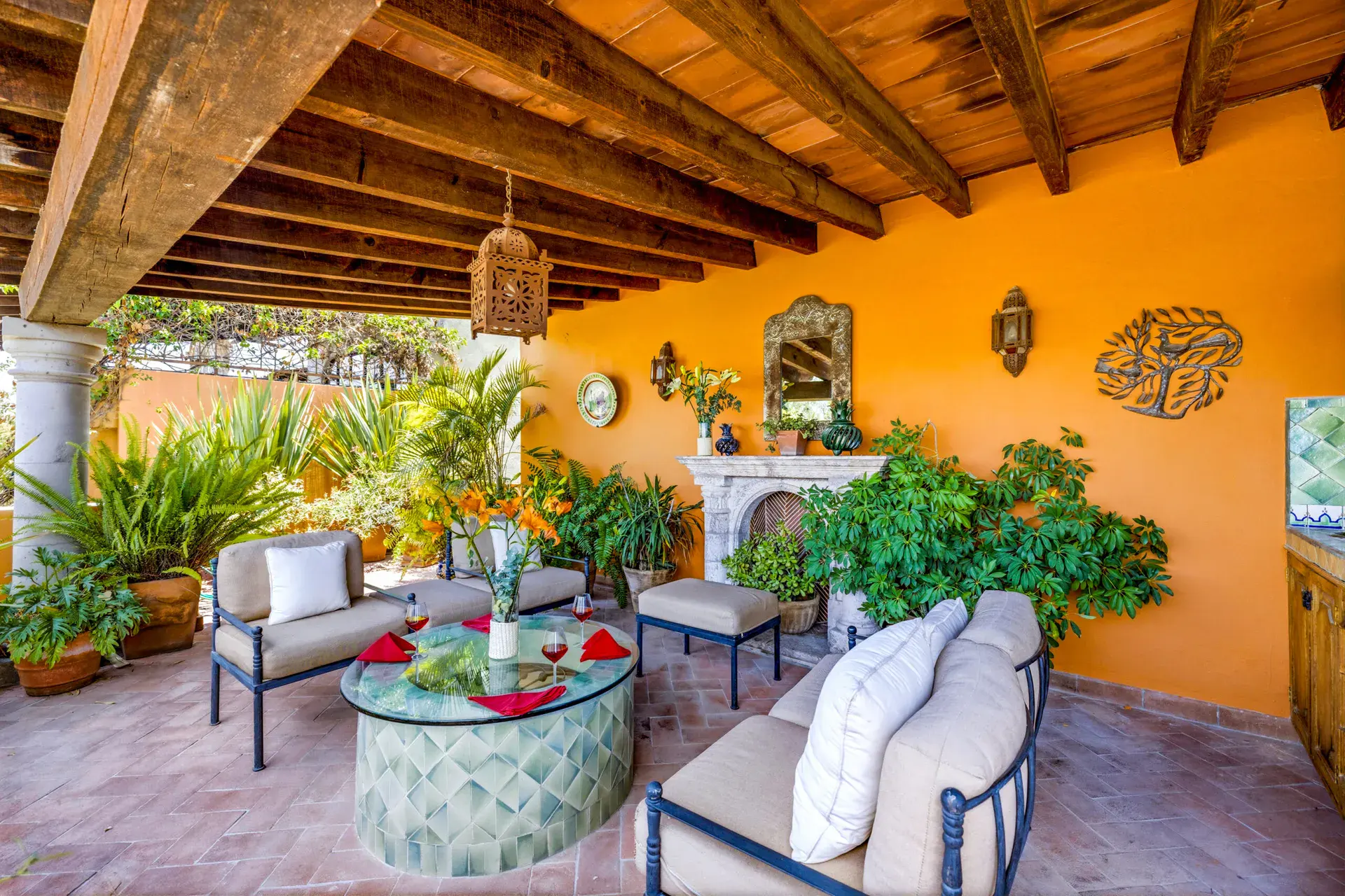Casa Cascada, upper covered lounge with a stone fireplace, outdoor sofas and a tiled coffee table, San Miguel de Allende