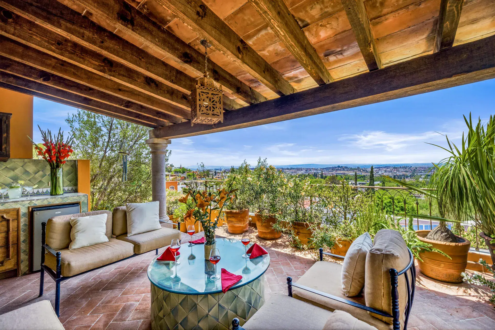 Casa Cascada, upper lounge under a wood beam ceiling with sofas, a glass table and a valley view, San Miguel de Allende