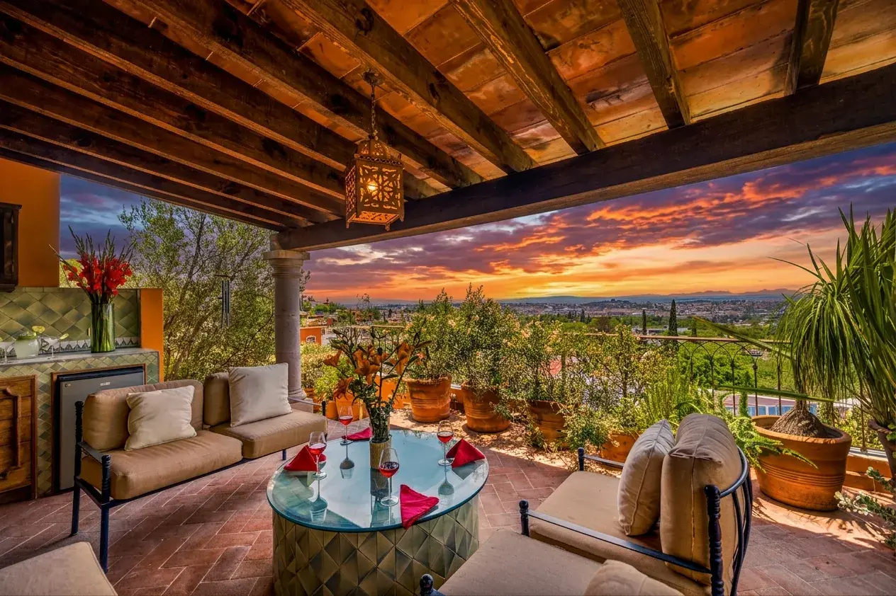 Casa Cascada, upper lounge at sunset with outdoor sofas, a glass table and a glowing sky, San Miguel de Allende