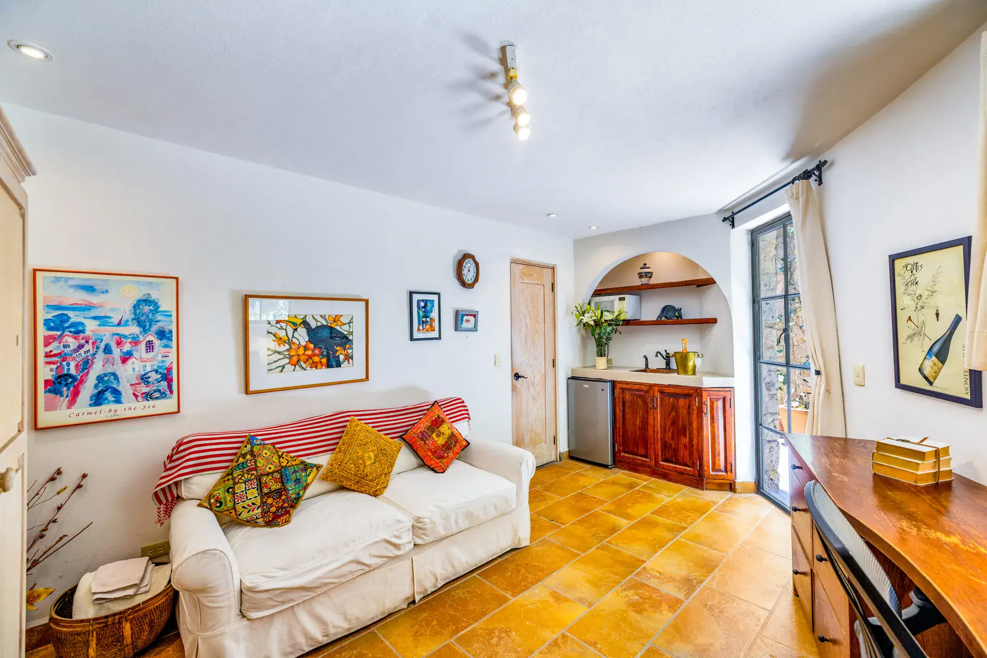 Casa Cascada, guest suite with a white sofa, framed art, a wet bar and a glass door, San Miguel de Allende