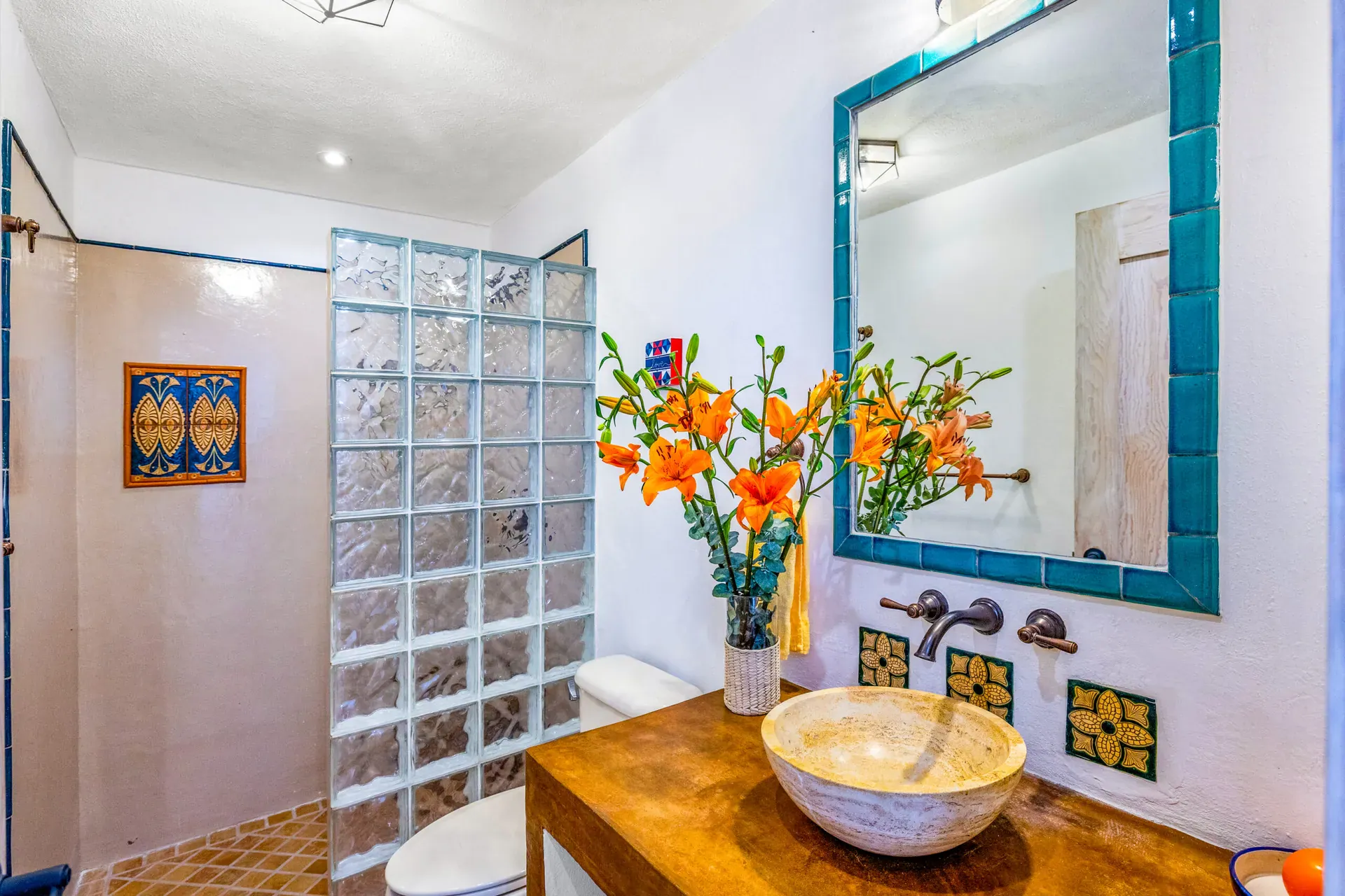 Casa Cascada, bathroom with a glass block shower, a stone vessel sink and a turquoise tile framed mirror, San Miguel de Allende