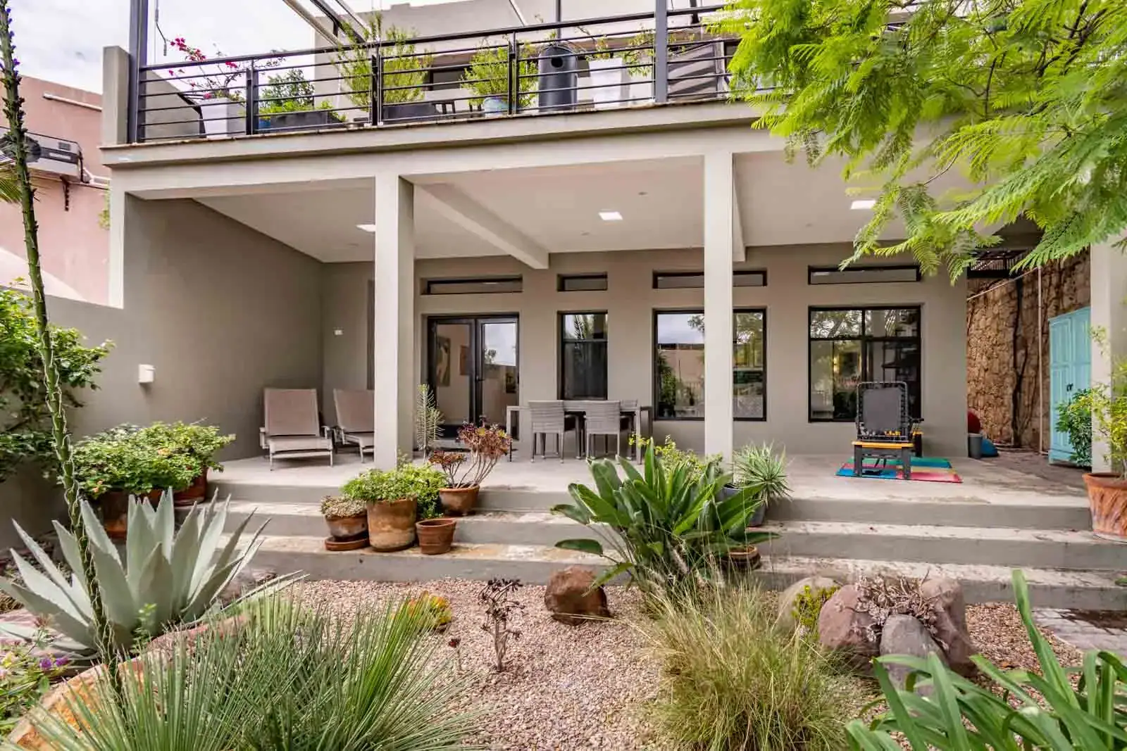 Casa Cielo Abierto, covered patio with lounge chairs, a dining table and a garden of agaves in front of the two-story house, San Miguel de Allende