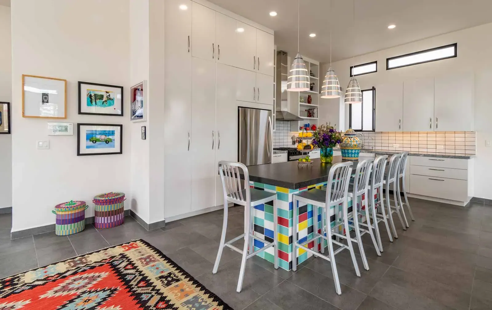 Casa Cielo Abierto, kitchen with white cabinets, a colorful tile-front island with white bar stools and a red kilim rug, San Miguel de Allende