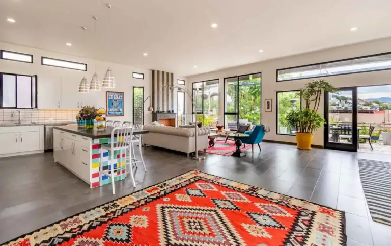 Casa Cielo Abierto, open-plan kitchen and living room with a red kilim rug, a tall window wall and garden doors, San Miguel de Allende