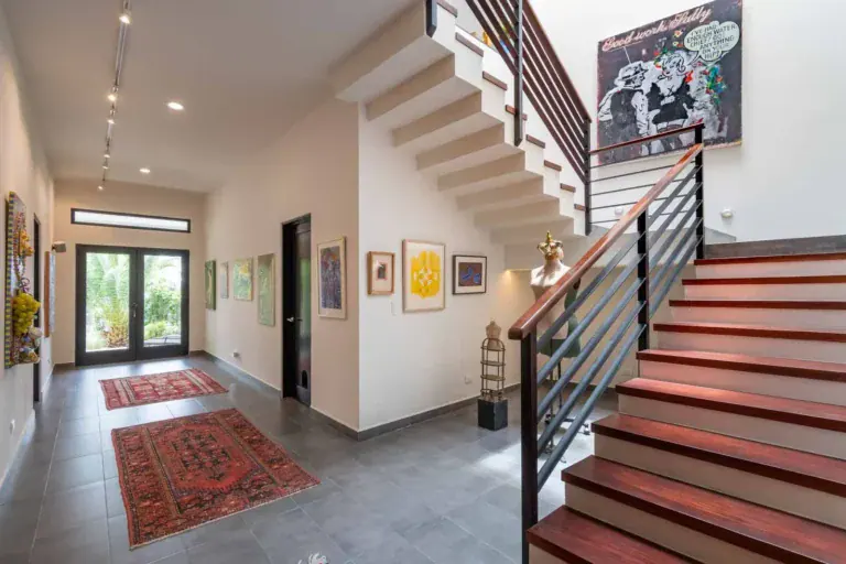 Casa Cielo Abierto, entry hall with a floating staircase, a red wood handrail, framed art and a glass front door, San Miguel de Allende