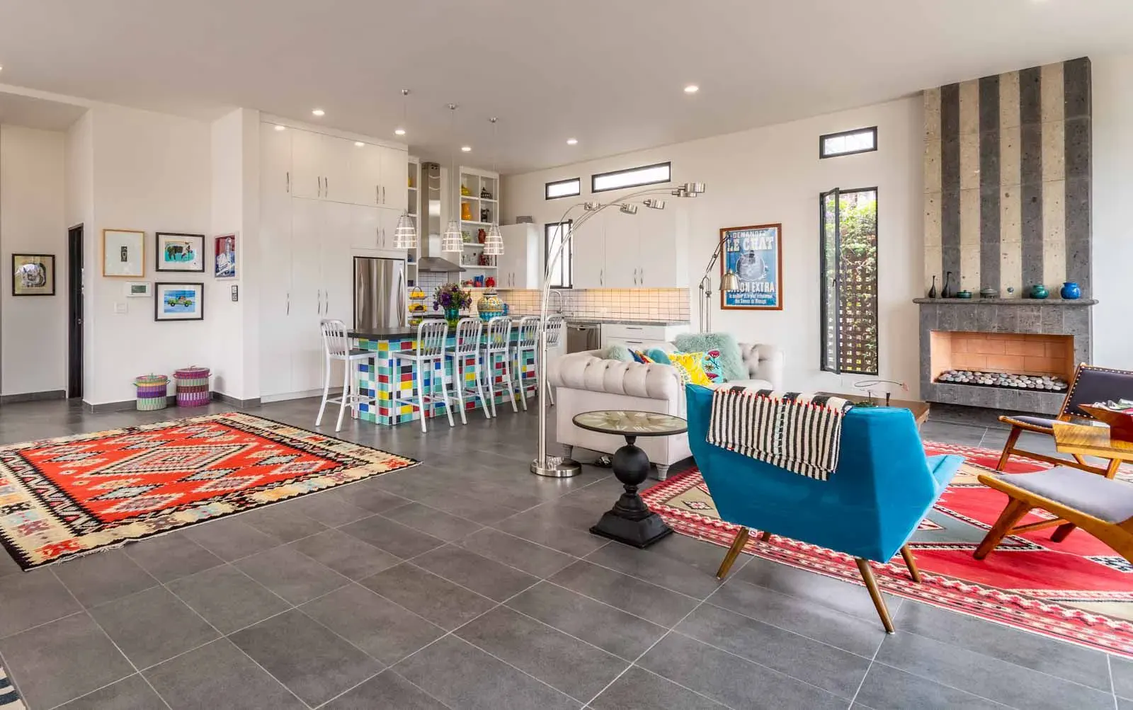 Casa Cielo Abierto, open-plan living area with a white tufted sofa, a blue armchair, a slate fireplace and a colorful kitchen island, San Miguel de Allende