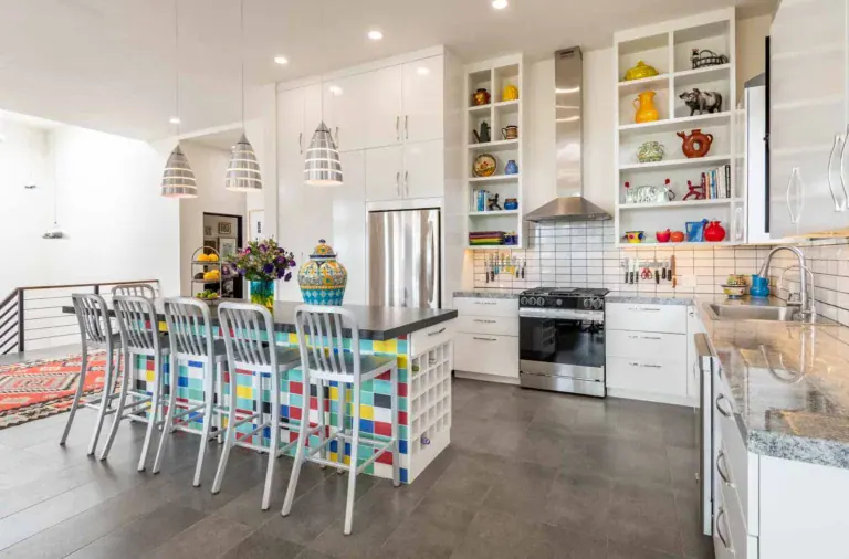 Casa Cielo Abierto, kitchen with a stainless range, a white subway tile backsplash, open shelves of colorful ceramics and a tiled island, San Miguel de Allende