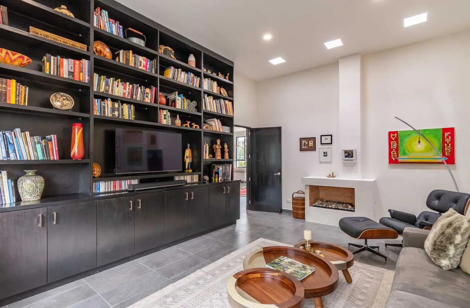 Casa Cielo Abierto, living room with a black built-in bookcase and television wall, a leather lounge chair and a fireplace, San Miguel de Allende