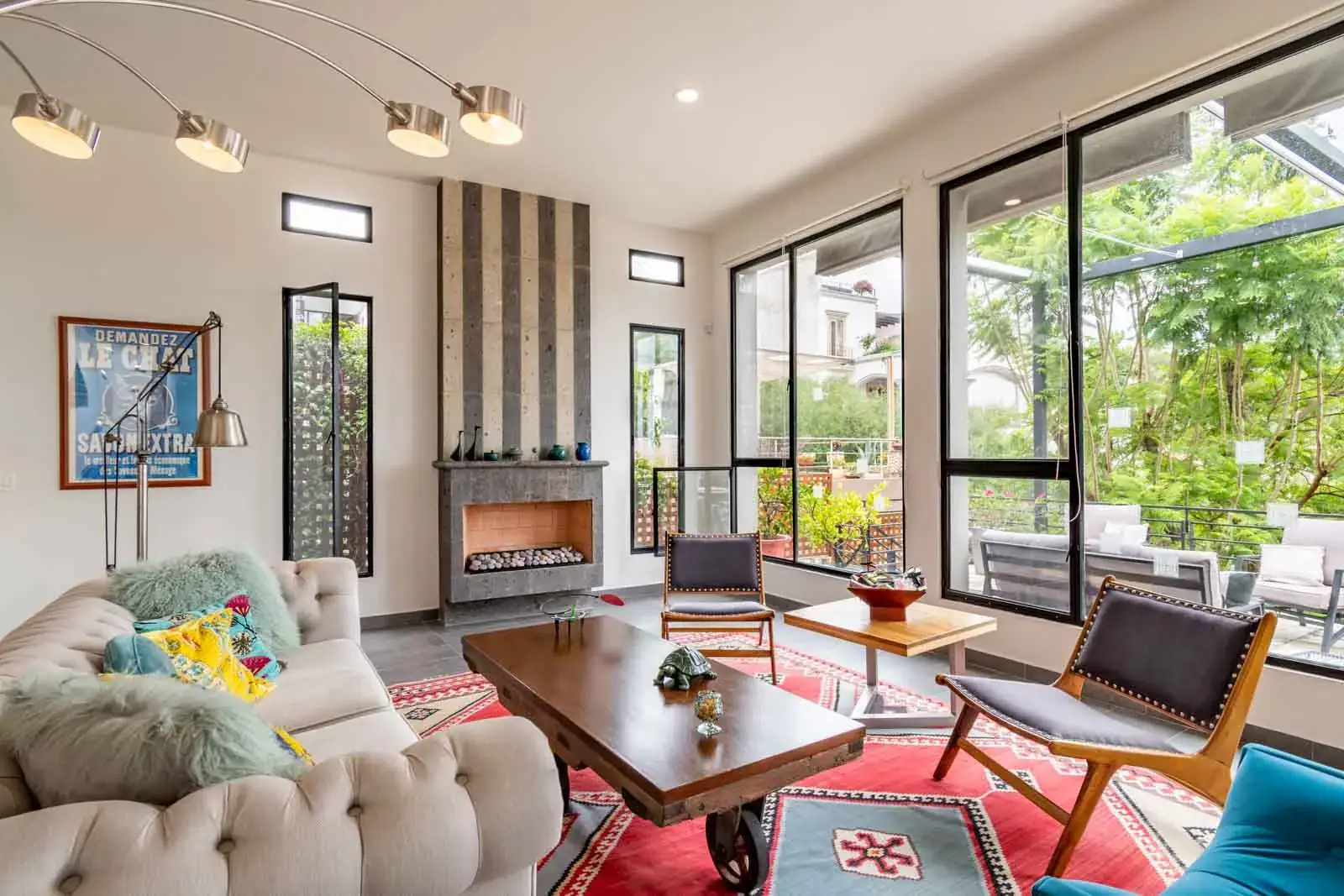 Casa Cielo Abierto, living room with a tufted sofa, a slate-clad fireplace and large windows to a patio, San Miguel de Allende