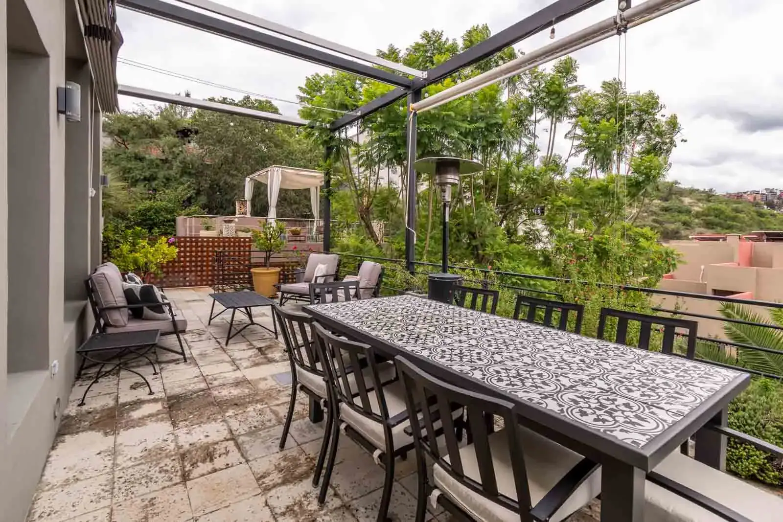 Casa Cielo Abierto, terrace with a long tiled dining table and a covered seating area overlooking the trees, San Miguel de Allende