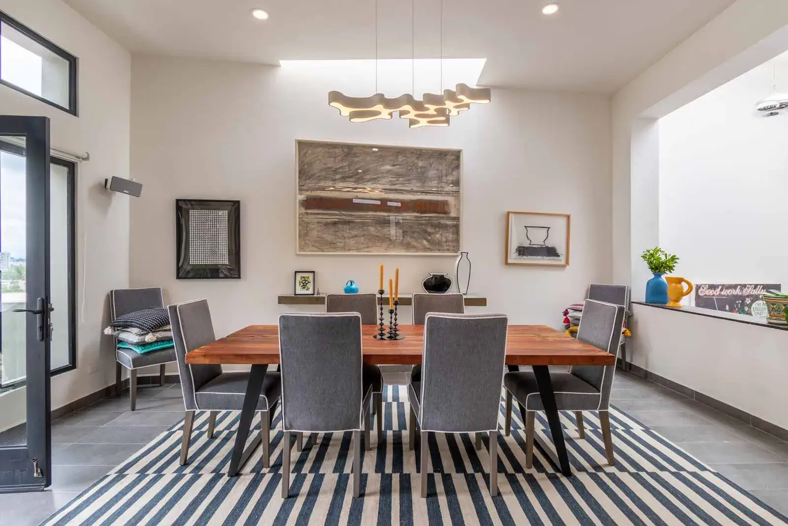 Casa Cielo Abierto, dining room with a wood table, gray chairs, a striped rug and a modern light fixture, San Miguel de Allende