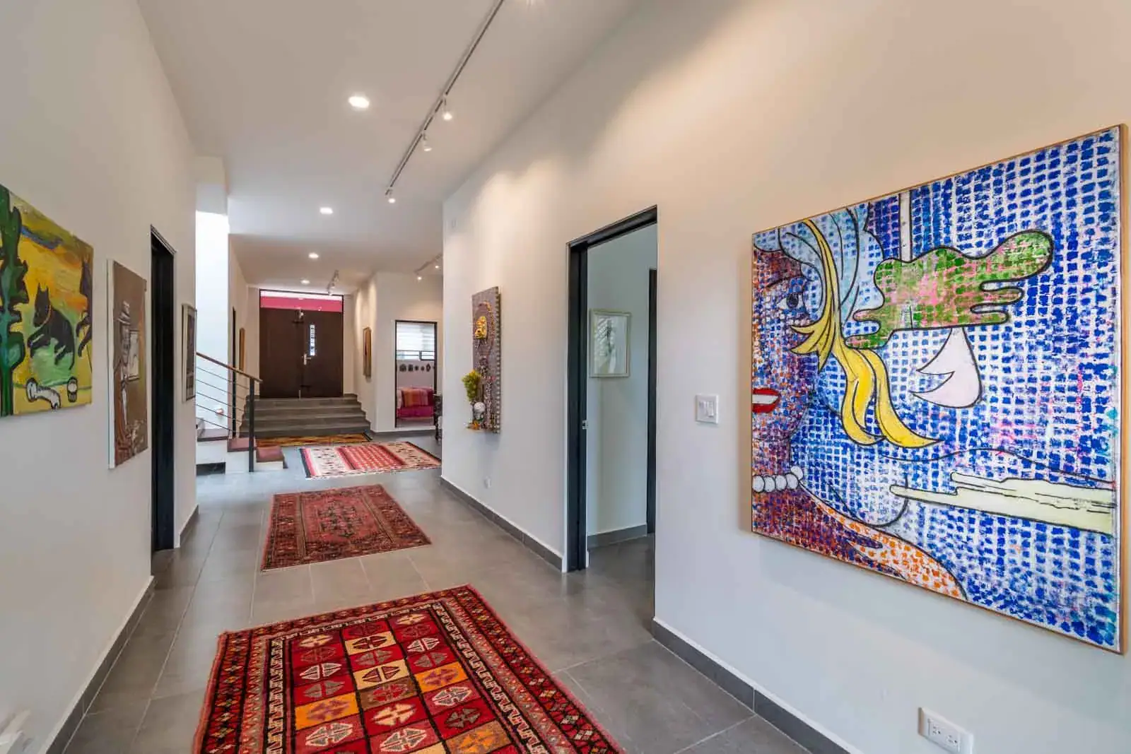 Casa Cielo Abierto, hallway with a large pop art painting, red rugs and a view to the front door, San Miguel de Allende