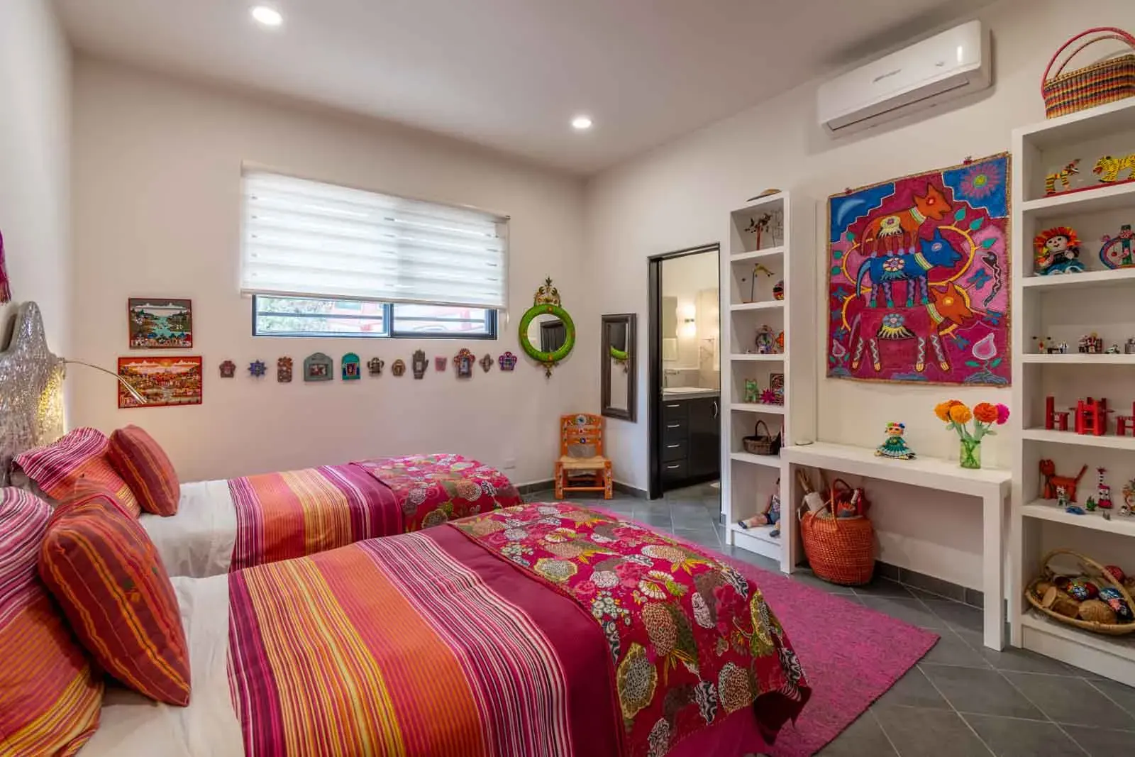 Casa Cielo Abierto, children's bedroom with twin beds in striped bedding, colorful folk art and shelves of toys, San Miguel de Allende