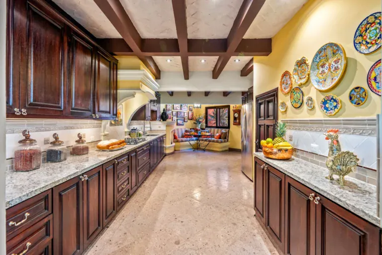 Casa Cleo Petra, kitchen with dark wood cabinets, granite counters and a plate collection, San Miguel de Allende